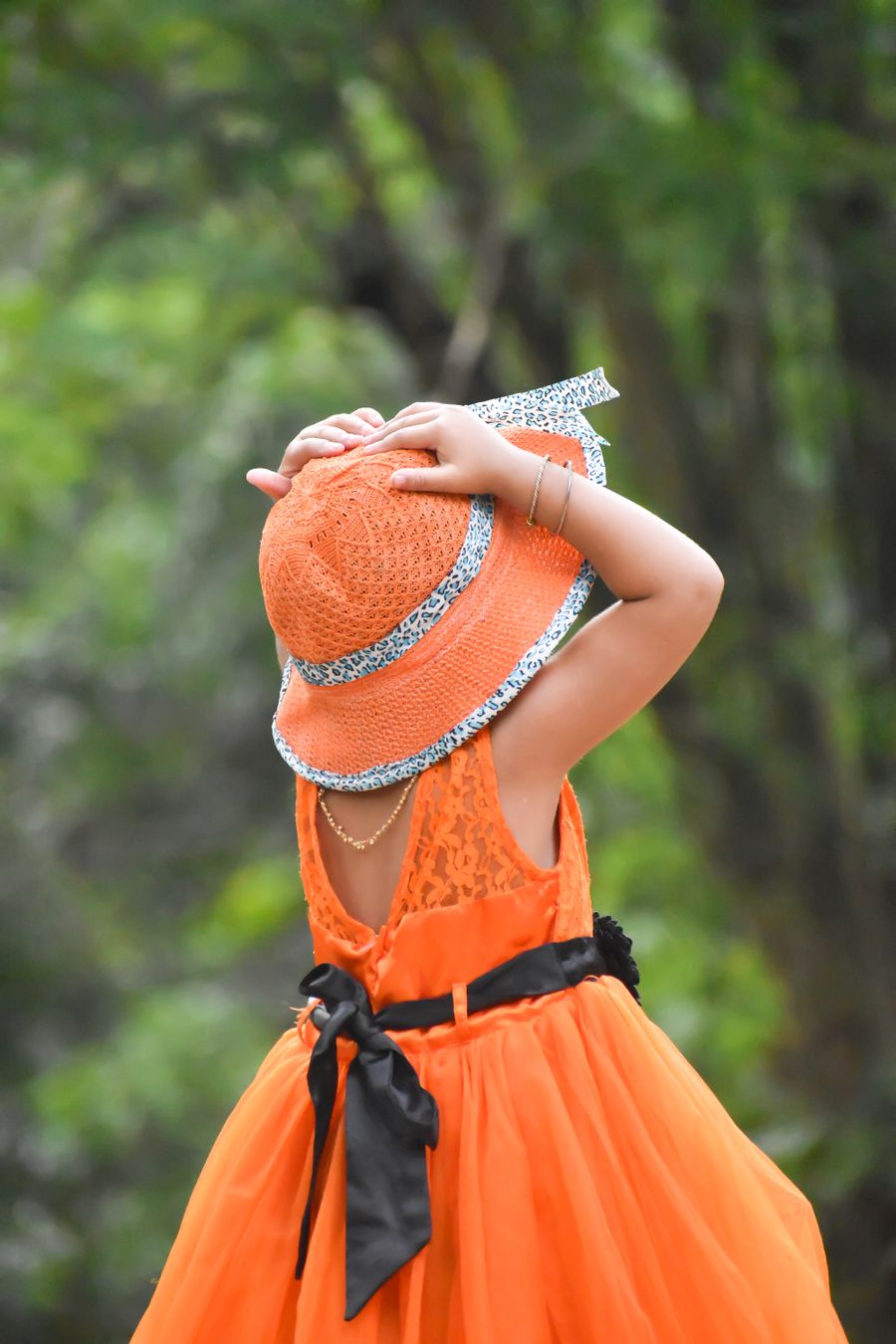 Girl in an orange dress and sun hat in a park