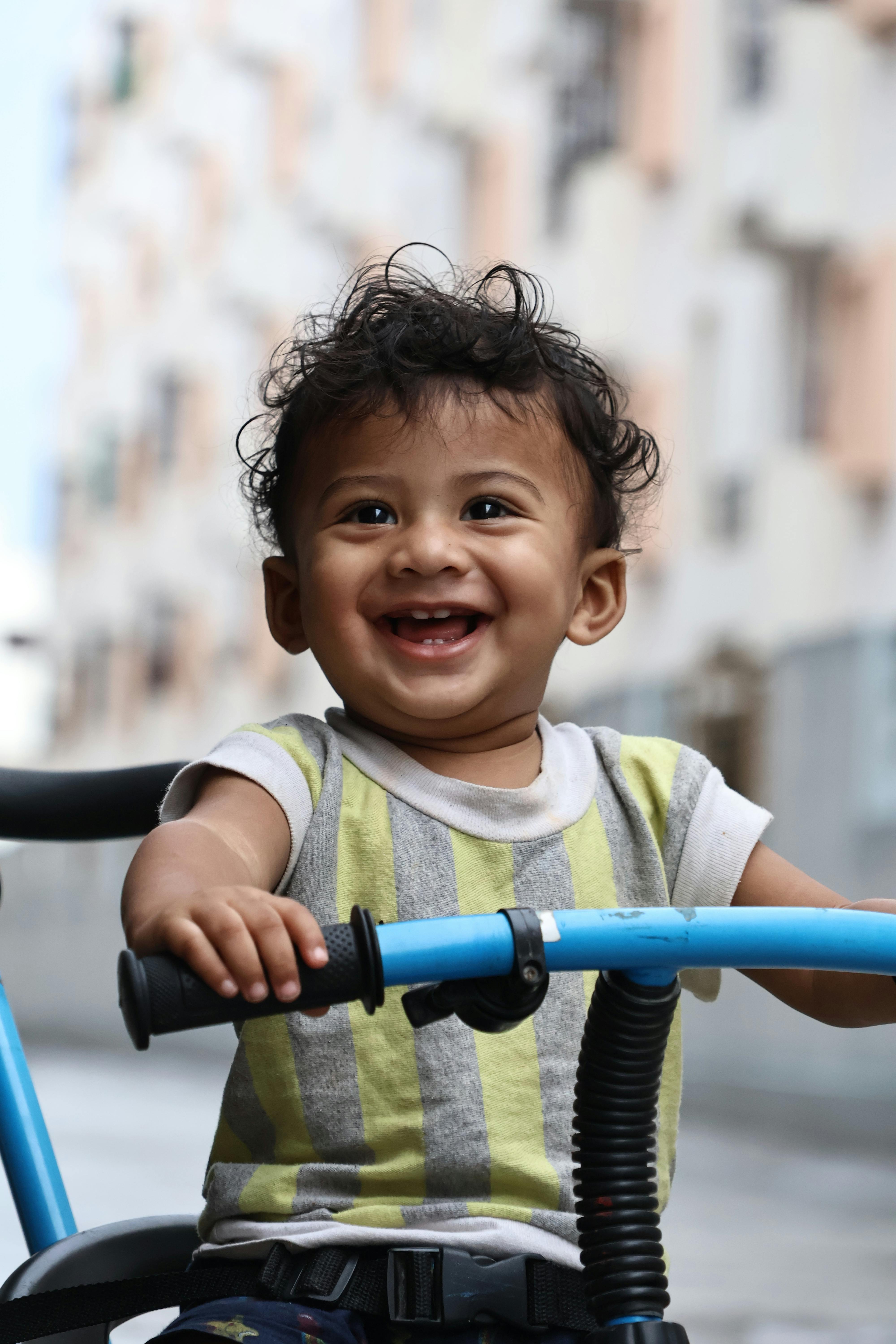 a smiling child riding a bike in the city