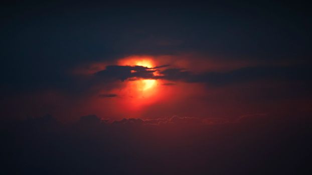 A dramatic sunset with glowing red colors and dark clouds creating a mystical silhouette.