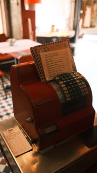 A vintage red cash register in a retro cafe interior with soft warm lighting, capturing nostalgia.