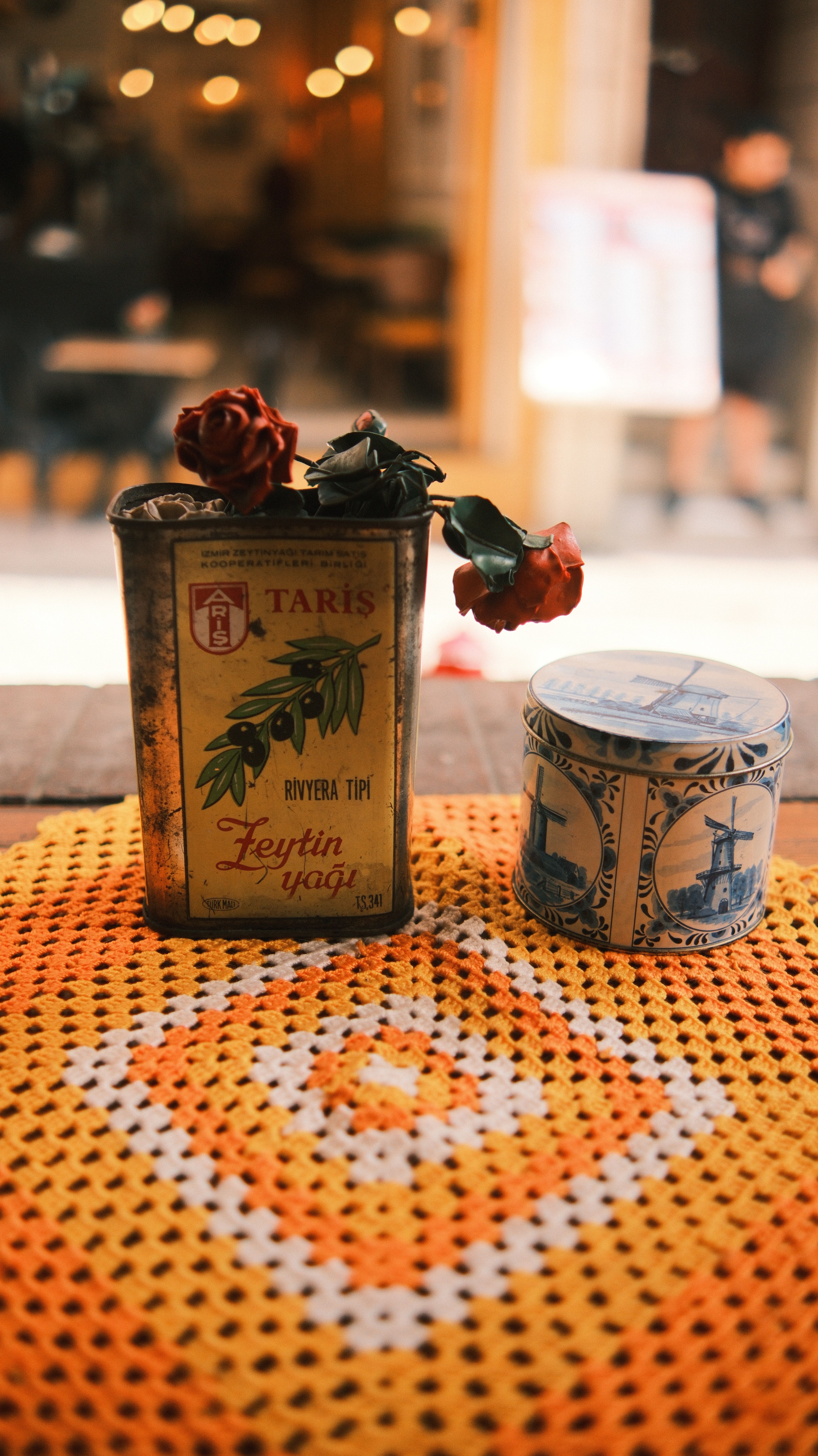 Retro olive oil tin and decorative blue container on a crochet table mat.