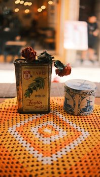 Retro olive oil tin and decorative blue container on a crochet table mat.