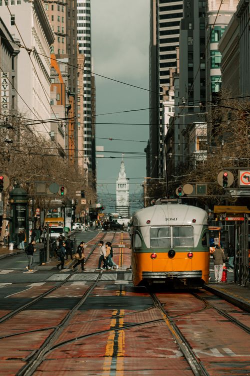 Free Vintage San Francisco cable car traveling on a bustling city street with iconic architecture. Stock Photo