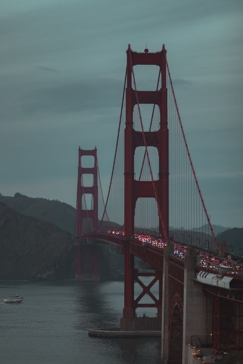 Free The Golden Gate Bridge in San Francisco at dusk with traffic and a serene water backdrop. Stock Photo