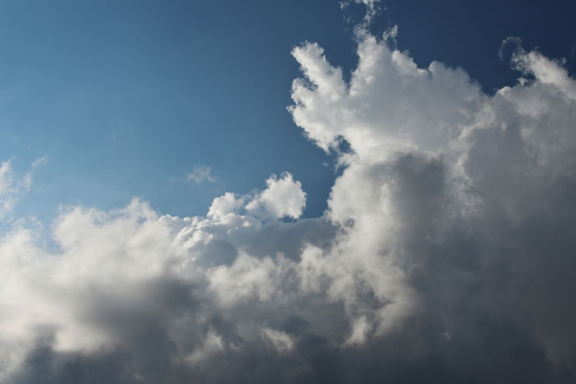 A plane flying through the clouds with a blue sky · Free Stock Photo
