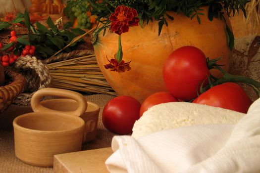 A warm, rustic setup with tomatoes, cheese, and autumn harvest decor creating a cozy scene.