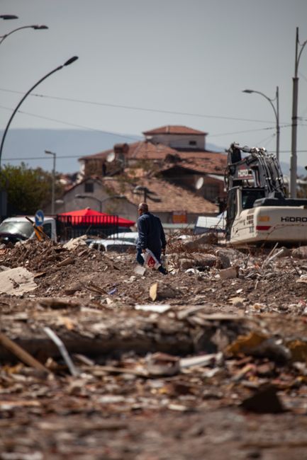 Photo by Seyfettin Geçit A man walks through a demolished urban area in Malatya, Türkiye, amidst debris and construction equipment.