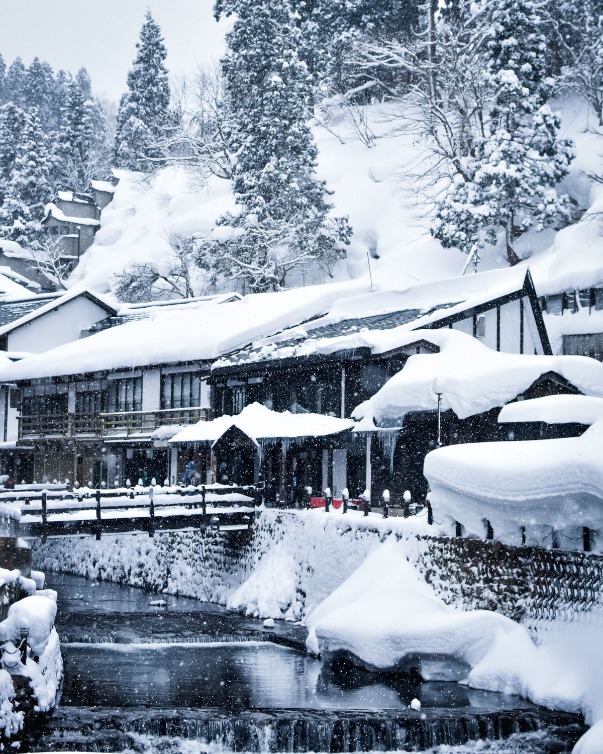 A traditional Japanese village blanketed in snow beside a river in winter