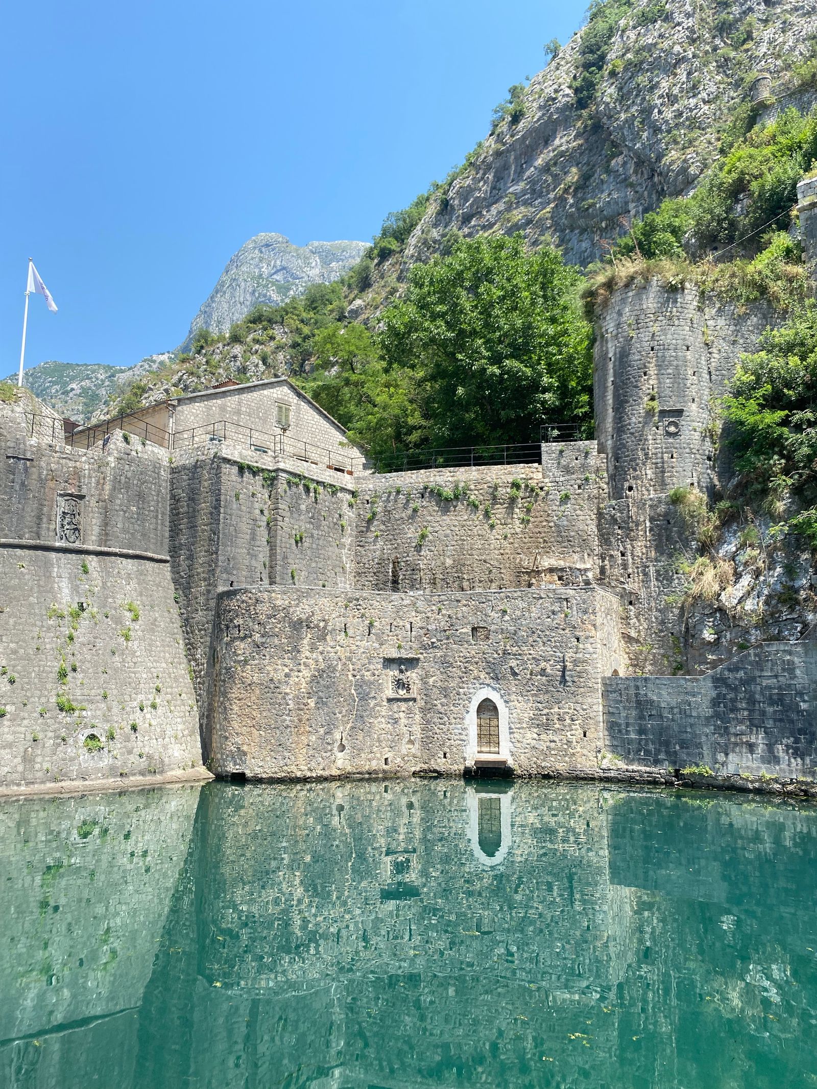 Kotor's stone fortification walls reflected in the bay