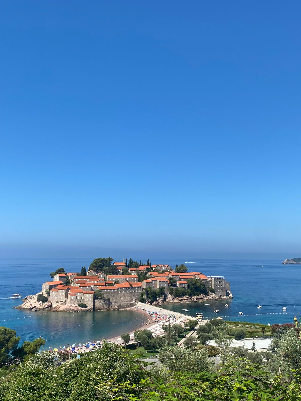 Iconicul ostrov Sveti Stefan cu apa albastră a Adriaticii într-o zi senină de vară