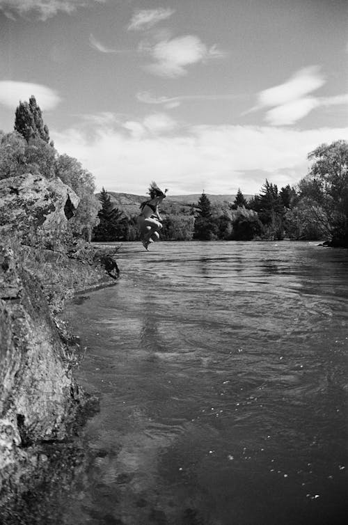 A black and white photo of a person jumping into the water