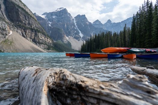 Scenic view of canoes moored on Moraine Lake with mountains and forest backdrop in Banff National Park.