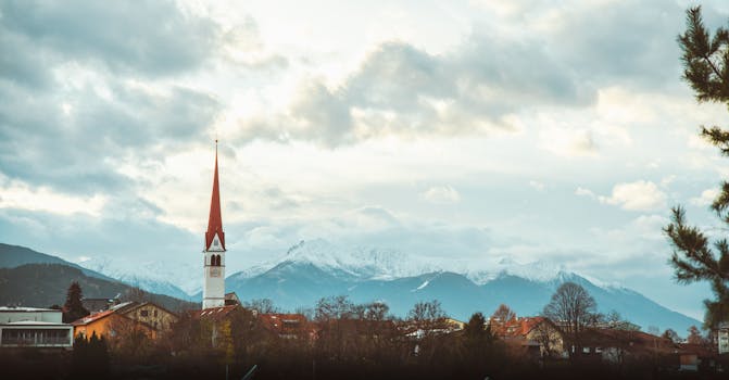 Majestic snowy mountains with a prominent church tower under a bright winter sky.