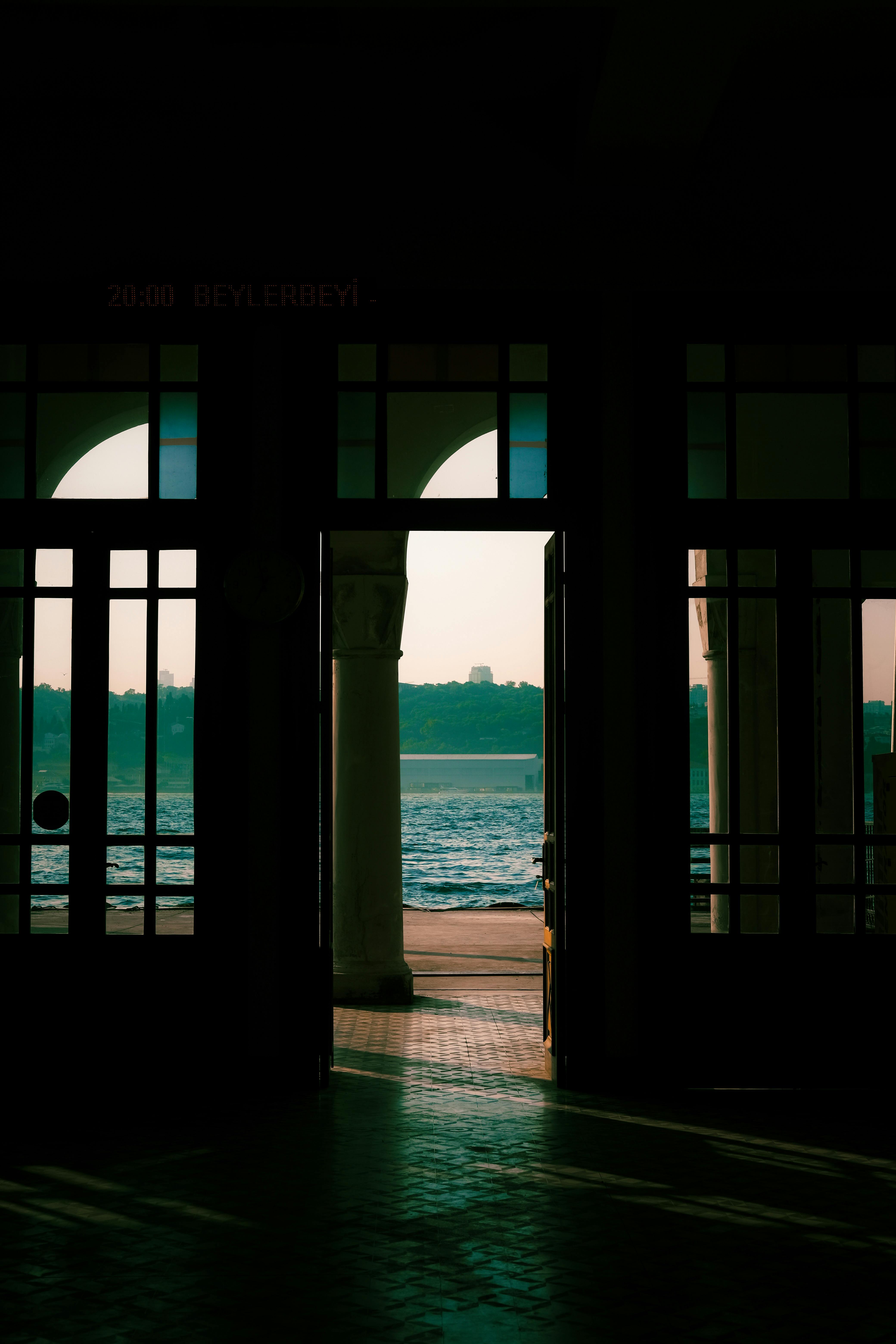 A serene view of the ocean through a doorway at sunset, capturing reflections and shadows.
