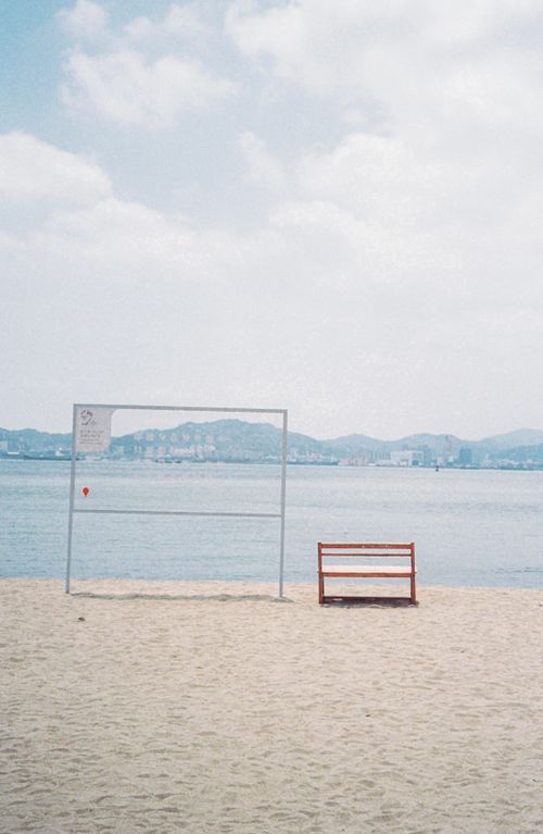 Free An empty volleyball court and bench on a tranquil sandy beach by the ocean. Stock Photo
