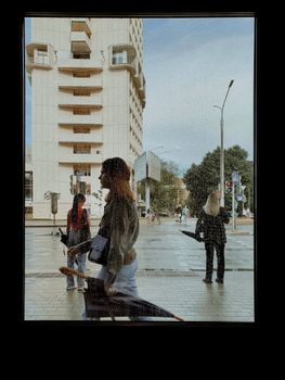 People walking near a contemporary building, captured through raindrop-covered glass.