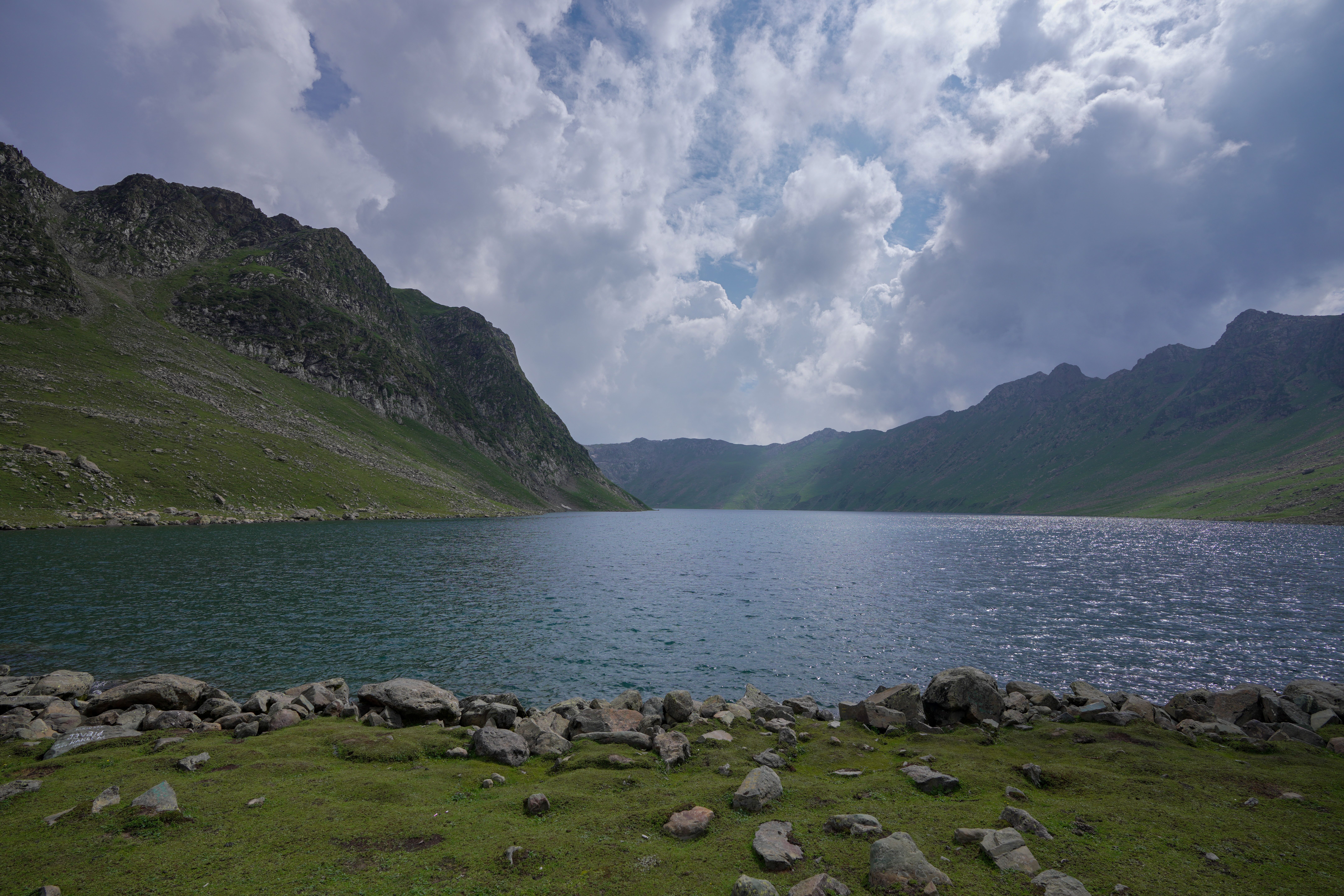 A lake surrounded by mountains and grass · Free Stock Photo
