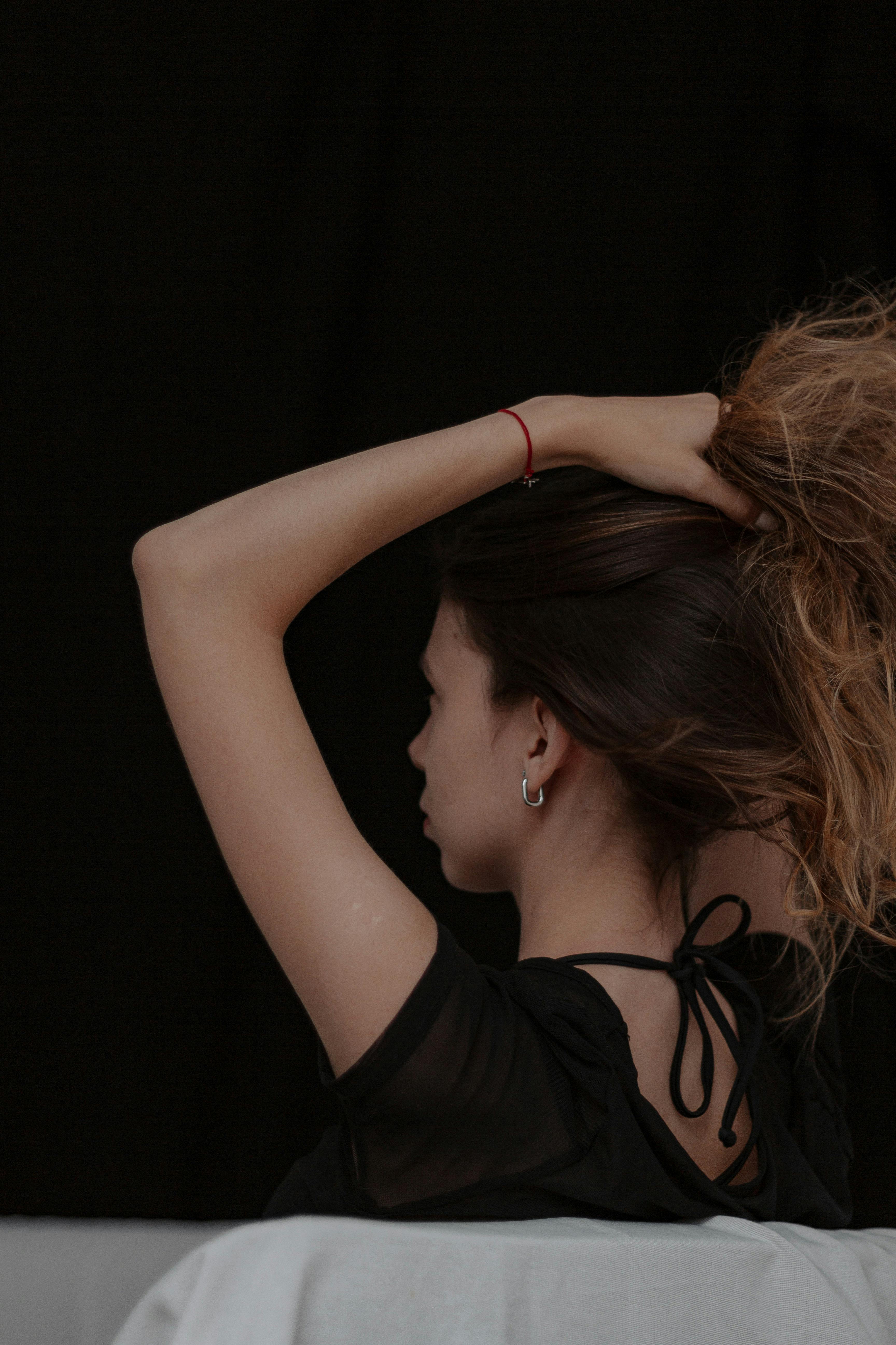 Stylish side profile of a woman with her hair tied up against a dark backdrop.