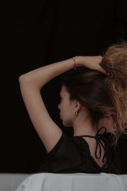 Stylish side profile of a woman with her hair tied up against a dark backdrop.