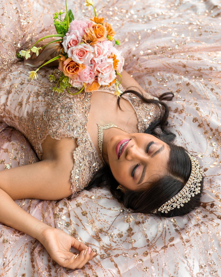 Brunette Woman In Crown And Dress Lying Down With Flowers