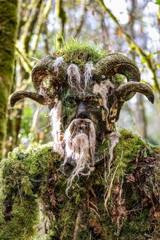 A mysterious moss-covered creature with horns blends into the forest surroundings.
