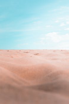 Peaceful desert landscape with soft sand dunes contrasting a vibrant blue sky, capturing serenity and simplicity.