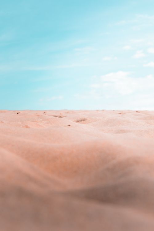 Free Peaceful desert landscape with soft sand dunes contrasting a vibrant blue sky, capturing serenity and simplicity. Stock Photo