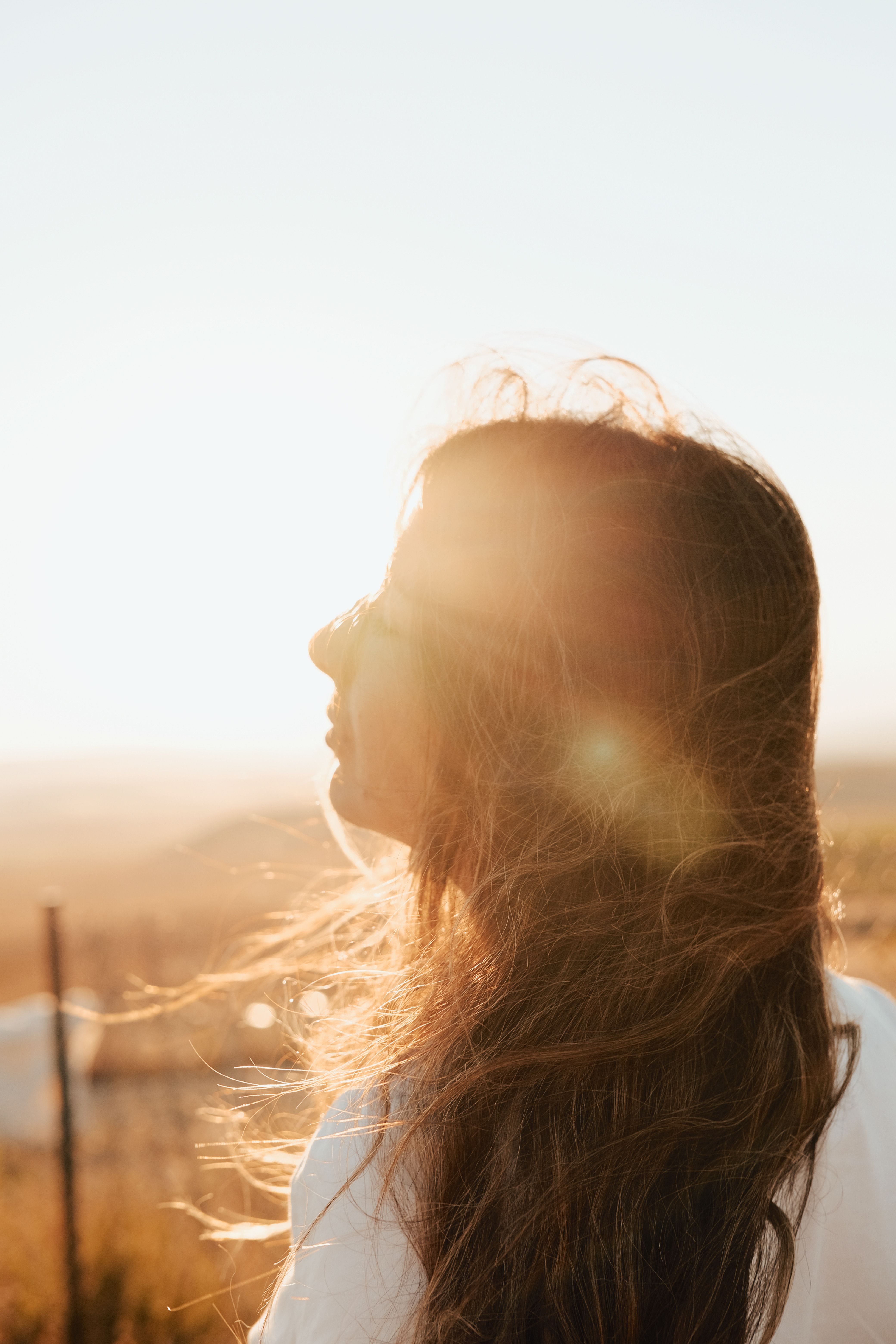 A woman with her hair blowing in the wind at sunset · Free Stock Photo