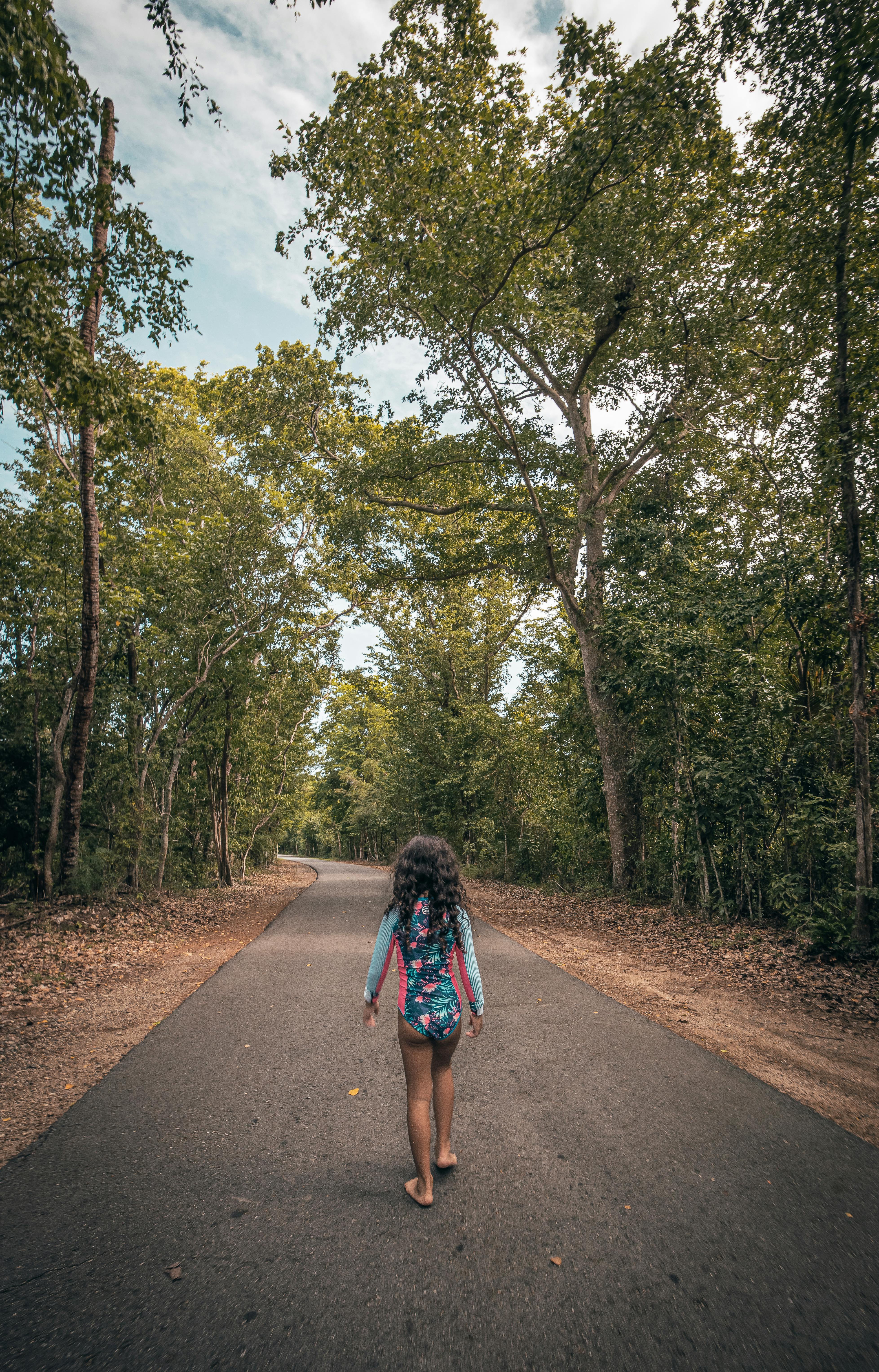 Young girl walking on a serene forest road in Fajardo, Puerto Rico during summer.