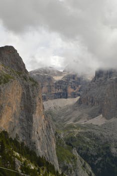 Breathtaking view of the Dolomites in Selva di Val Gardena, Italy with clouds and cliffs.