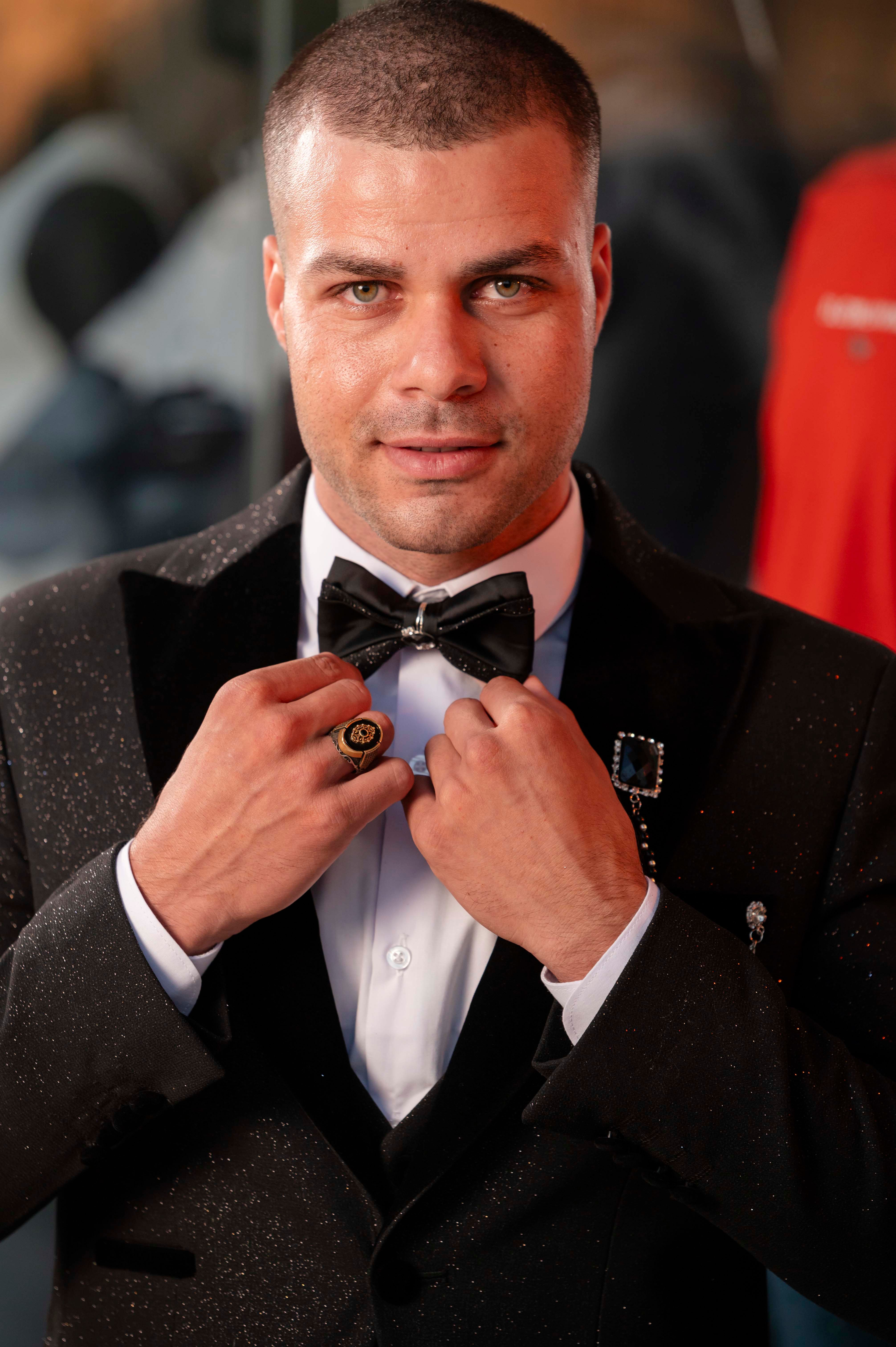 A man in a suit adjusting his bow tie · Free Stock Photo