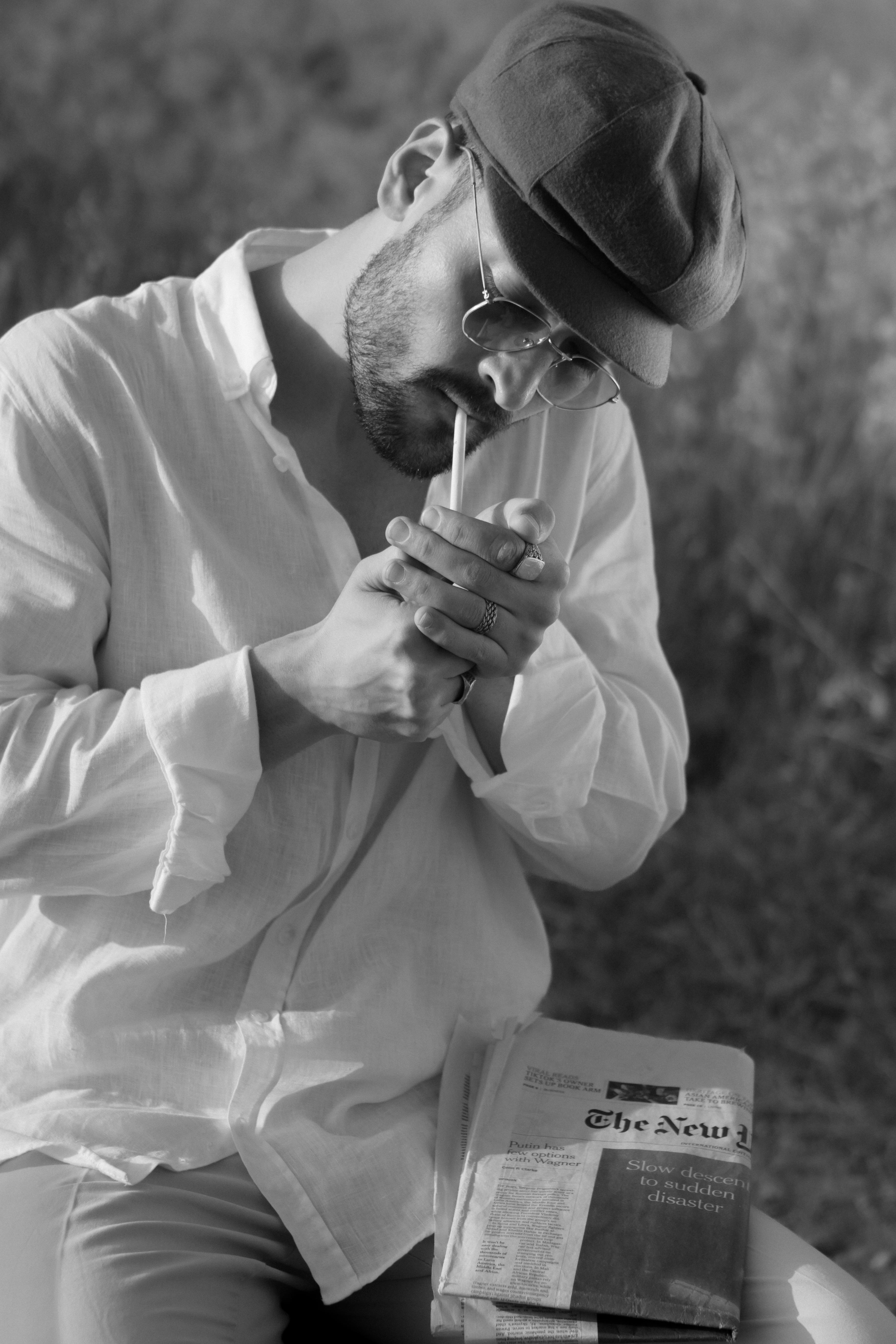 Black and white portrait of a man lighting a cigar, featuring vintage style and street fashion.