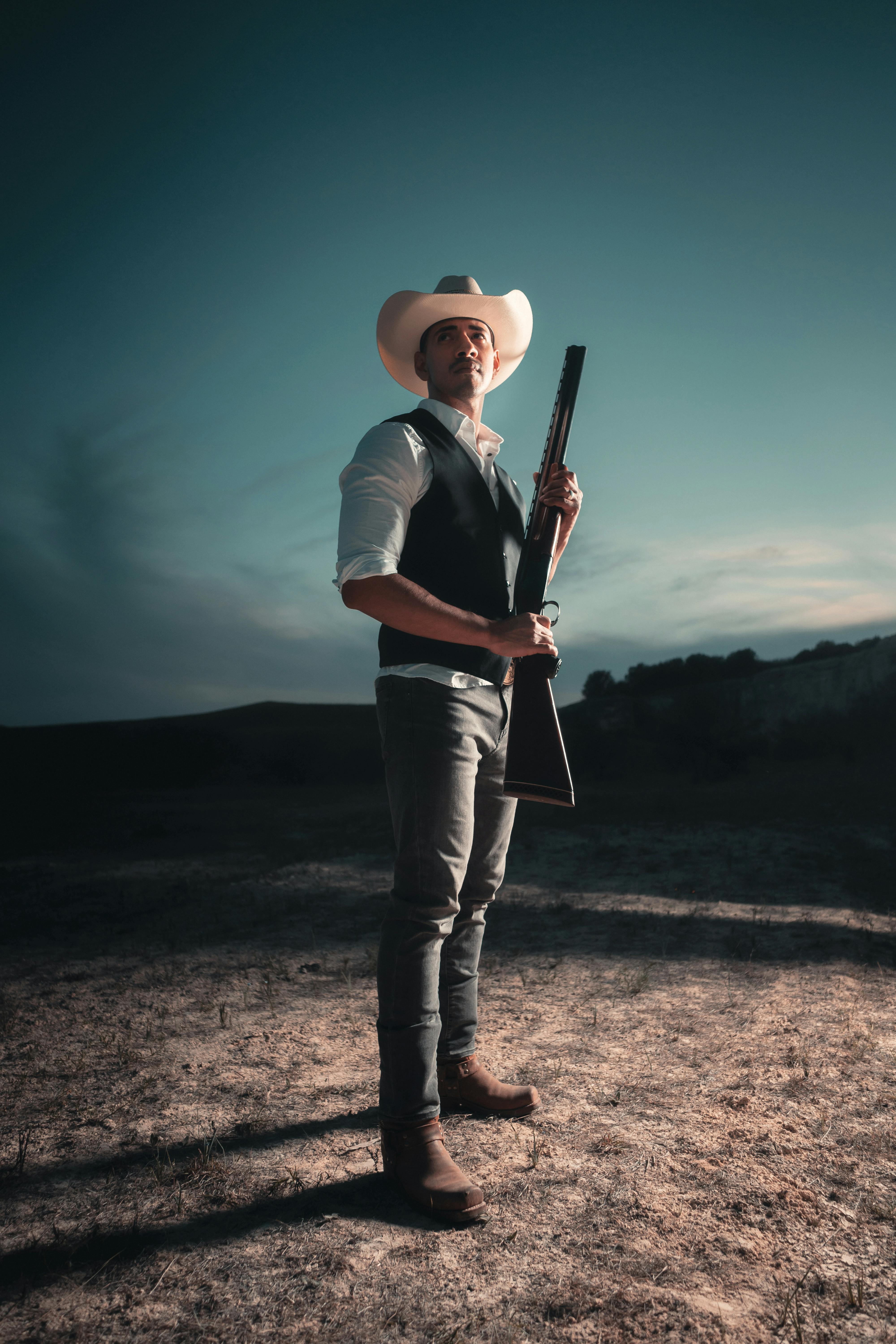 Cowboy standing with shotgun at night