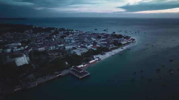 A stunning aerial view of Zanzibar's coastline at twilight, showcasing the city's architecture and ocean.