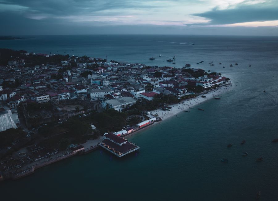 A stunning aerial view of Zanzibar's coastline at twilight, showcasing the city's architecture and ocean.