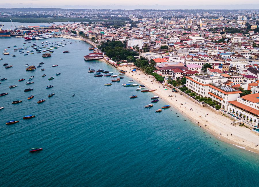 Stunning aerial view of Zanzibar Stone Town's coastline with boats and vibrant cityscape.