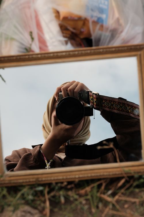 Free Artistic portrait using mirror reflection showing a photographer capturing an image outdoors. Stock Photo