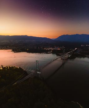 A breathtaking aerial view of Vancouver, BC at twilight with the Lions Gate Bridge and city lights.