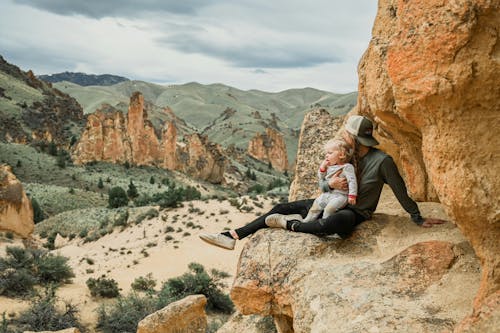 Woman with a Little Child Sitting on a Rock and Looking at the Hills 