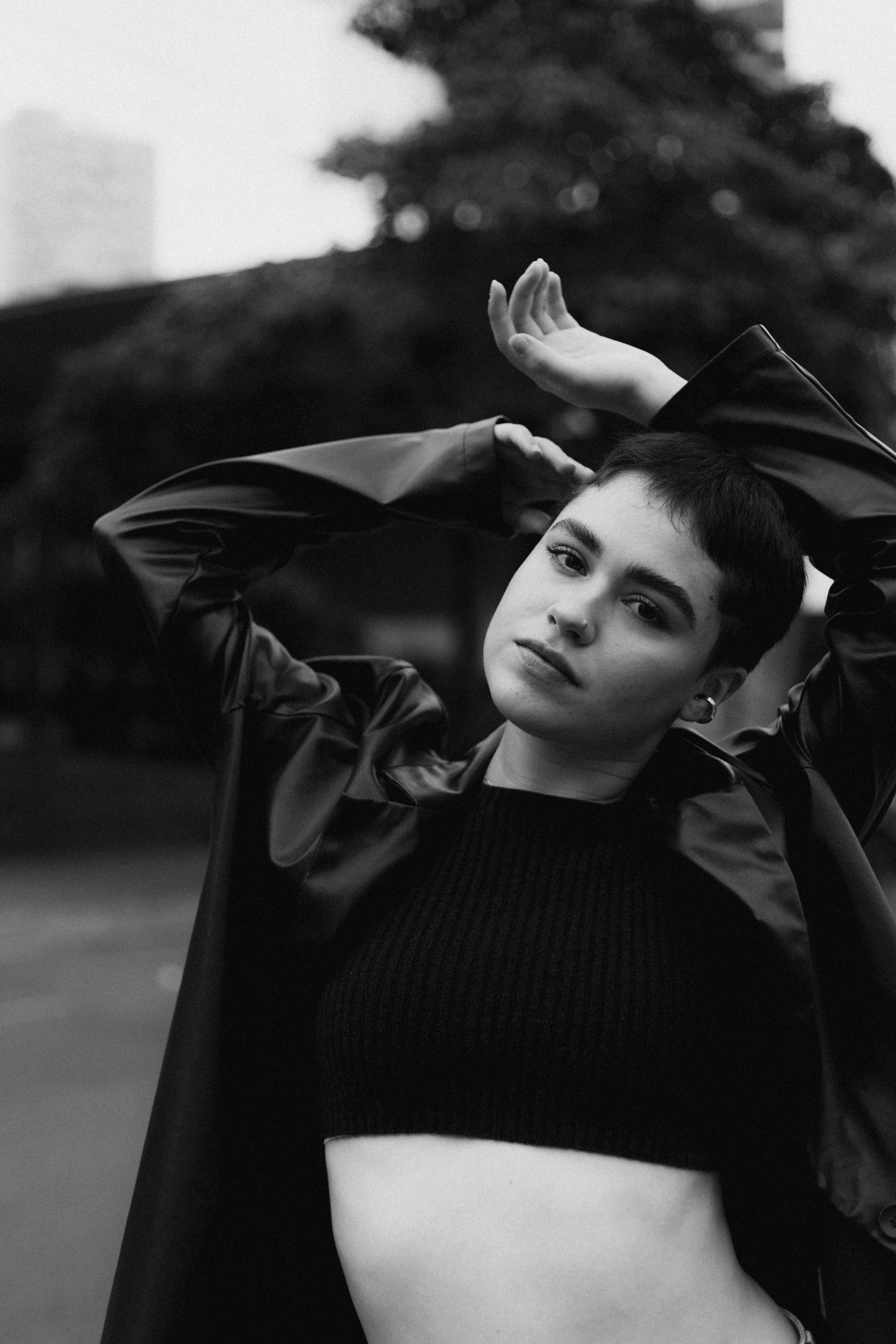 A captivating black and white portrait of a model posing outdoors in fashionable attire.