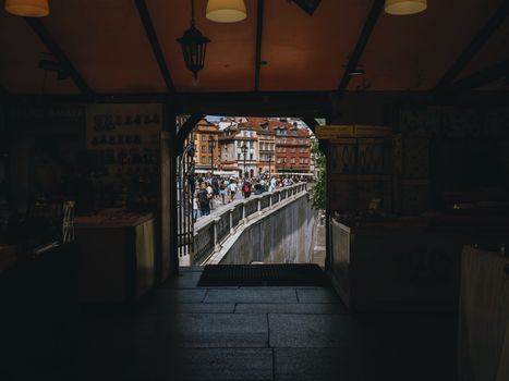 A view from a dark interior through an archway to a bustling urban scene.