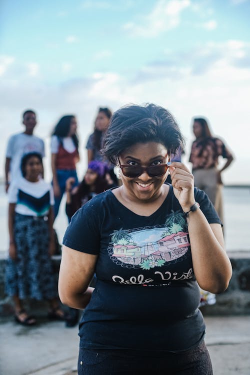 Free A woman in a black shirt and sunglasses standing in front of a group of people Stock Photo