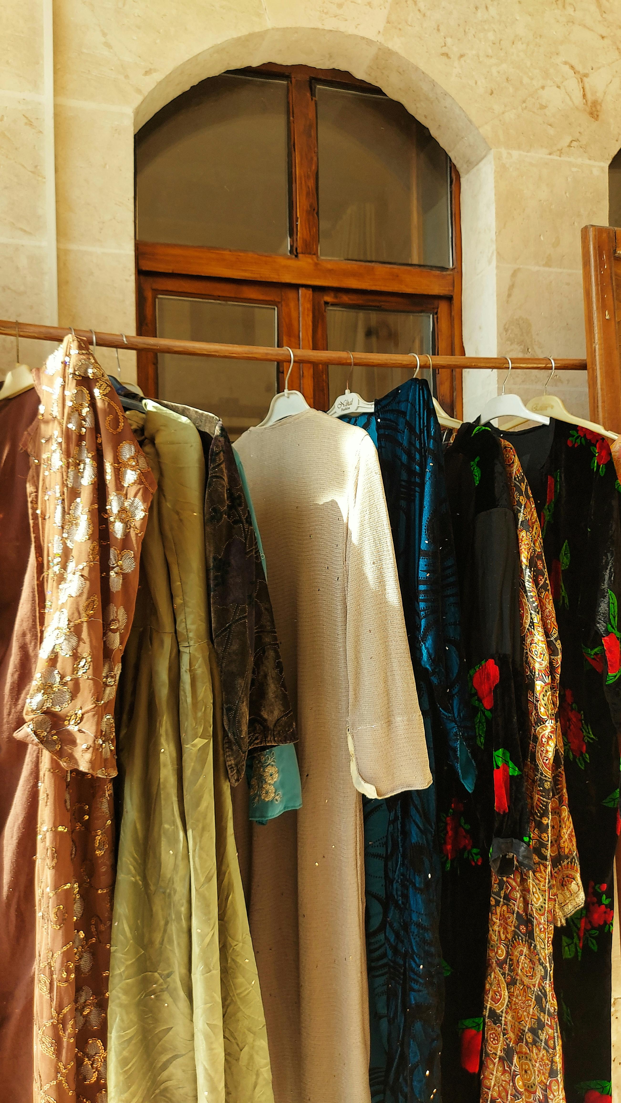 Vibrant traditional dresses hanging under the sun in a historic setting in Şanlıurfa, Türkiye.