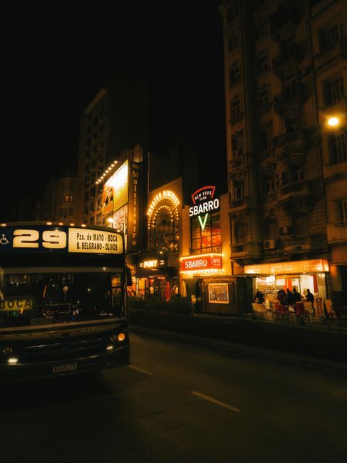 Bustling Buenos Aires city streets at night featuring Sbarro and a local bus.