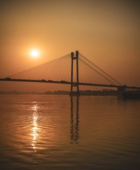 A stunning view of Vidyasagar Setu in Kolkata, India, silhouetted against a glowing sunset.