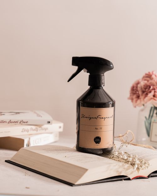 Free Elegant still life featuring a spray bottle, books, and flowers in a soft, muted setting. Stock Photo