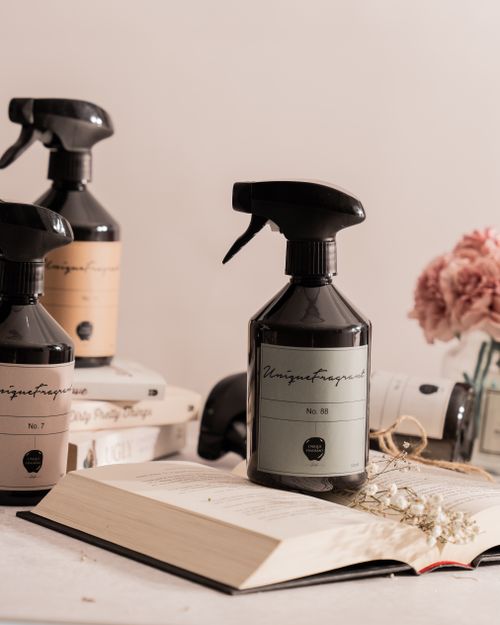 Free Stylish spray bottles of fragrance with pink flowers and books for a clean, modern aesthetic. Stock Photo