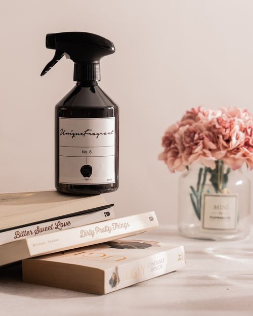 Free Stylish arrangement of fragrance bottle with books and flowers on a table. Stock Photo