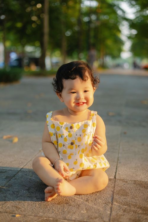 Free Cute Asian toddler sitting and smiling in a park in Bắc Giang, Vietnam during the day. Stock Photo