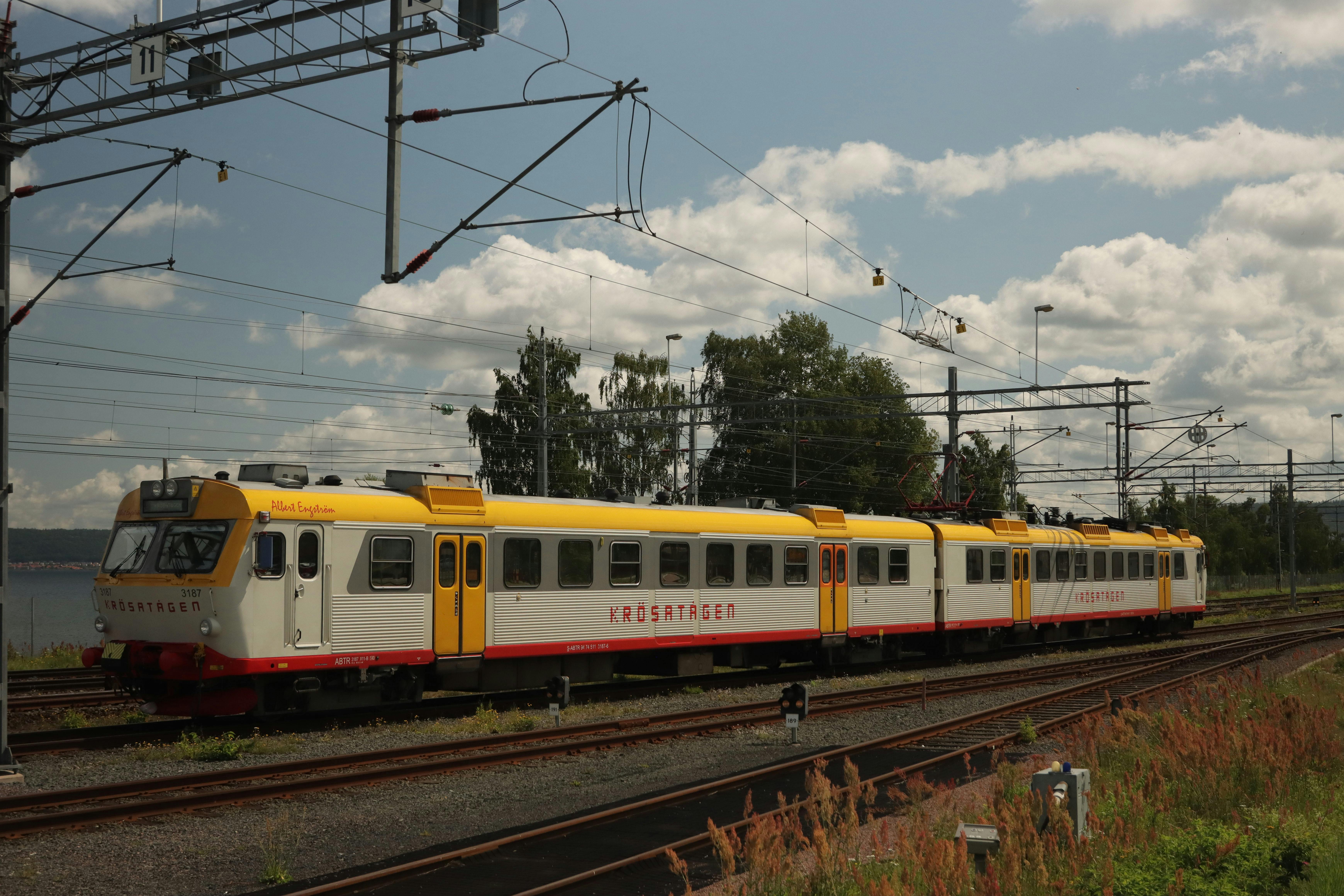 Free Colorful train on tracks in rural Jönköping, Sweden under clear skies. Stock Photo